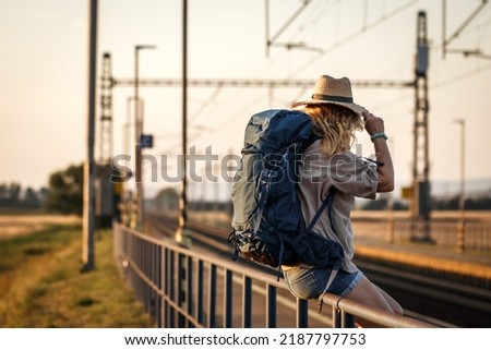 Travel at vacation. Woman with backpack waiting for train at railway station