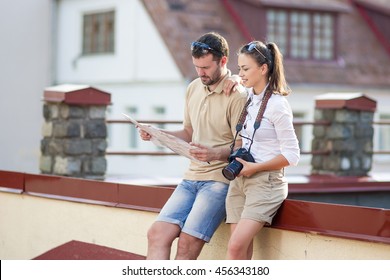 Travel And Vacations Concepts. Happy Young Couple Traveling Together. Exploring City Map In City. Horizontal Image Orientation