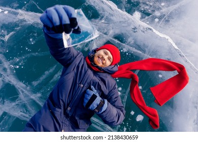 Travel Winter Lake Baikal, Smile Man Tourist In Red Cap Lie On Ice.