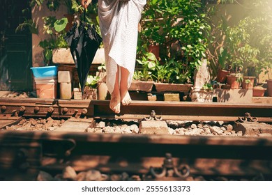 Travel, woman and barefoot adventure on railway for holiday exploration, freedom and sightseeing destination. Tourist, person and umbrella on train track with balance, weekend trip and free spirit - Powered by Shutterstock