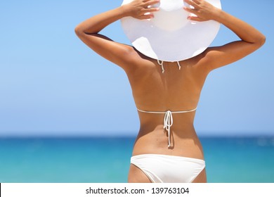 Travel Woman On Beach Enjoying Blue Sea And Sky Wearing White Beach Sun Hat And Bikini. Beautiful Pretty Stylish Young Asian Model From Behind On Vacation Holidays.