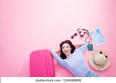 travel woman smile happily and look somewhere lying on pink floor