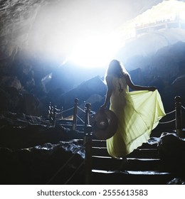 Travel, woman and walking in mountain cave for holiday adventure, sightseeing or exploring Vietnam. Back, tourist fashion or stairs for underground destination, lens flare or curious in dark location - Powered by Shutterstock