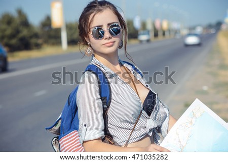 Travel - young woman with car look at road map on a highway against sky
