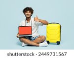 Traveler amazed IT Indian man wear white casual clothes sit hold blank screen laptop pc computer isolated on plain blue background. Tourist travel abroad in free time rest getaway Air flight concept