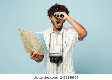 Traveler amazed Indian man wear white casual clothes hold read map use binocular isolated on plain blue background Tourist travel abroad in free spare time rest getaway Air flight trip journey concept - Powered by Shutterstock