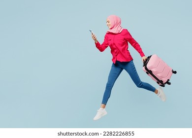 Traveler arabian asian muslim woman wear pink abaya hijab hold mobile cell phone bag isolated on plain blue background Tourist travel abroad in free time rest getaway. Air flight trip journey concept. - Powered by Shutterstock