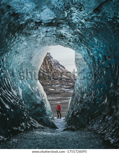 Traveler with a backpack in an ice cave. Man\
standing on the glacier Vatnaj kull in Iceland. Epic landscape in\
Iceland. Travel and adventure\
concept.