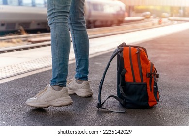 Traveler with backpack waiting for a train at trainstation. Travel concept.