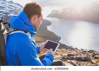 Traveler Backpacker Using Digital Tablet Computer Outside In Mountains, Mobile Travel Application Online