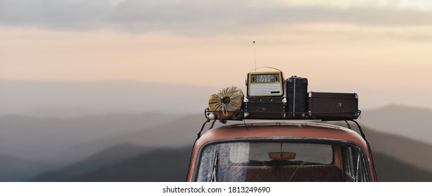 traveler car with roof rack and things in retro style on mountains background