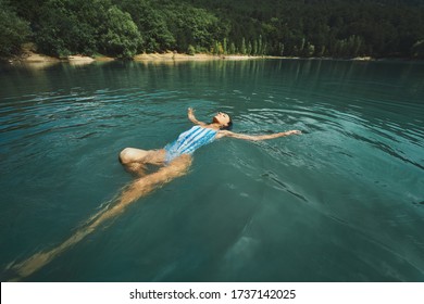 traveler carefree woman relaxing and floating in calm clear water, swimming on back in blue lake. Outdoor adventure, people in nature and calmness concept - Powered by Shutterstock