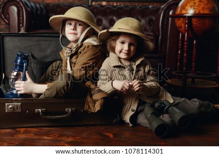 Traveler children in a travel suitcase are playing at home. Childhood. Fantasy, imagination. 