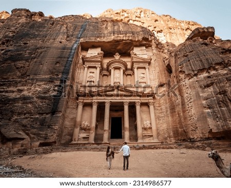 Traveler couple observing the Treasury or Al-khazneh in Petra, famous travel destination of Jordan and one of the seven wonders. Heritage of humanity by unesco.