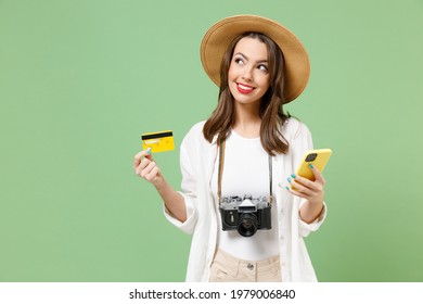 Traveler dreamful tourist woman in casual clothes hat camera hold mobile cell phone credit bank card isolated on green background Passenger travel abroad on weekends getaway Air flight journey concept