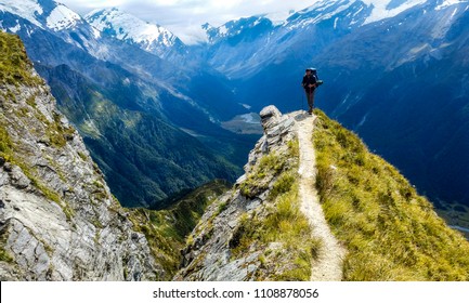 traveler at the edge of a cliff with amazing view behind him.Cascade Saddle, Mount Aspiring National Park, New Zealand