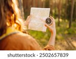 Traveler explorer young woman holding compass and a map in her hands on the forest. Adventure, vacation concept. Active lifestyle.