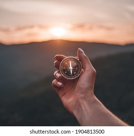 Traveler explorer young woman holding compass in a hand in summer mountains at sunrise, point of view. - Powered by Shutterstock