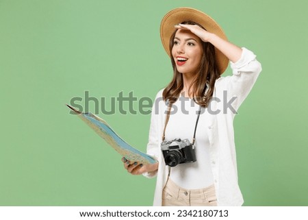 Traveler exploring tourist woman in casual clothes hat camera hold paper map look far away distance isolated on green background Passenger travel abroad weekends getaway Air flight journey concept.