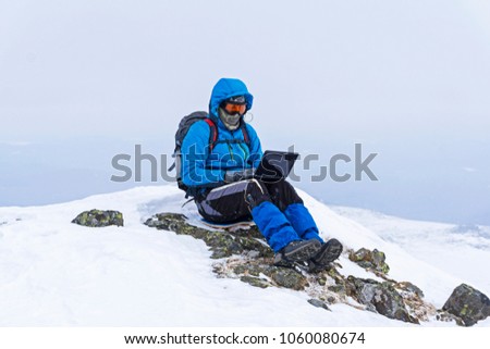 traveler freelancer works with a laptop in the winter in the wild mountains away from civilization