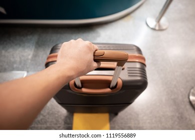 Traveler hand holding suitcase in an airport.