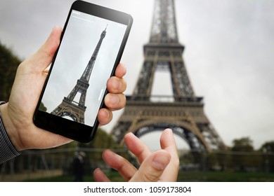 traveler hand taking a photo of Eiffel Tower with smartphone during a weekend trip to Paris, France