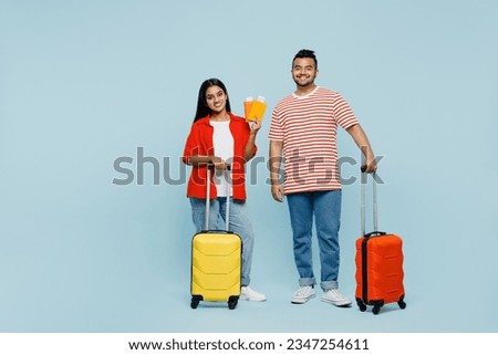 Traveler happy Indian man woman wear red casual clothes hold passport ticket bag isolated on plain blue color background Tourist travel abroad in free time rest getaway Air flight trip journey concept