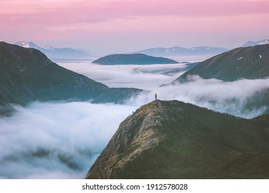Traveler hiking above mountain clouds enjoying Norway sunset landscape travel adventure lifestyle vacation outdoor epic trip