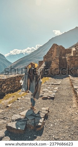 Traveler hipster girl in hat with backpack exploring ruins of Ollantaytambo Ruins in Sacred Valley of Peru