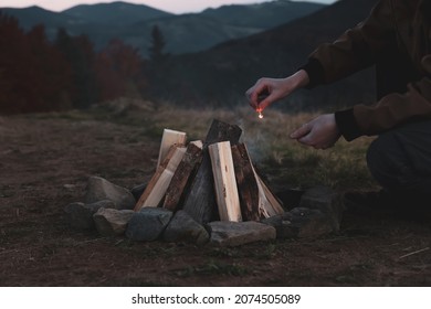 Traveler lighting up bonfire with matches outdoors in evening, closeup - Powered by Shutterstock