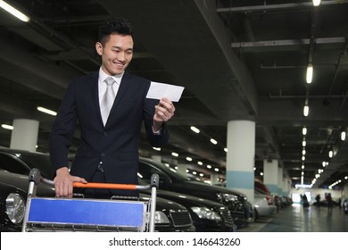 Traveler Looking At Ticket In Airport Parking Lot