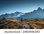 Traveler man with backpack hiking on summit of Mont Blanc massif and blue sky in French Alps at Chamonix, France