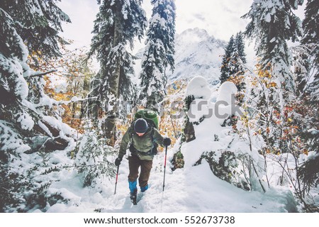 Traveler Man with backpack hiking in winter snowy forest landscape Travel Lifestyle concept adventure active vacations outdoor cold weather into the wild