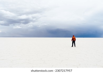 Traveler Man with Backpack Standing at Uyuni Salt Flats on Cloudy Day. Altiplano, Bolivia. Salt Formations. Wide Shot. Dramatic and Stormy Sky. Solo Traveling Concept. - Powered by Shutterstock