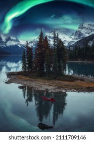 Traveler Man Canoeing On Spirit Island With Aurora Borealis Over Rocky Mountains In The Night At Jasper National Park, Alberta, Canada