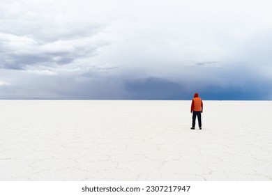 Traveler Man Standing at Uyuni Salt Flats on Cloudy Day. Altiplano, Bolivia. Dry Season. Salt Formations. Wide Shot. Dramatic and Stormy Sky. Solo Traveling Concept - Powered by Shutterstock