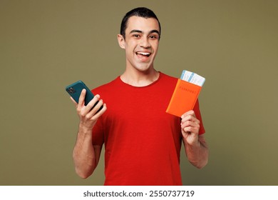 Traveler man wear red casual clothes hold passport ticket, mobile cell phone isolated on plain green color background. Tourist travel abroad in free time rest getaway. Air flight trip journey concept - Powered by Shutterstock