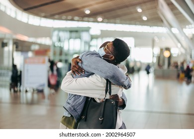 Traveler Man And Woman Giving Warm Embrace At Airport Arrival Gate. Woman Getting Warm Welcome Hug From Man At Airport.