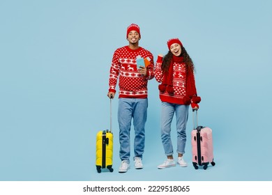 Traveler merry couple two man woman wear red Christmas sweater hat holding valise passport ticket isolated on blue background Tourist travel abroad in free time New Year 2023. Air flight trip concept - Powered by Shutterstock