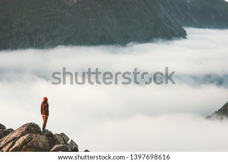 Traveler on cliff above clouds travel hike in mountains alone adventure extreme summer trip outdoor Norway vacations