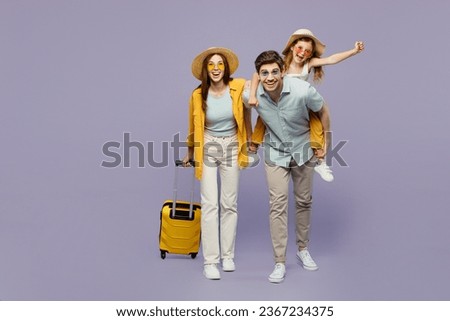 Traveler parents mom dad with child girl wear casual clothes hold bags, sit on back isolated on plain purple background. Tourist travel abroad in free time rest getaway Air flight trip journey concept