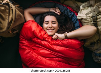The traveler is resting in a sleeping bag. Rest concept. A tourist is resting in a tent. Woman relaxing in sleeping bag. Travel, camping concept, adventure. Happy smiling female traveler. The Traveler