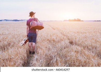 Traveler,  Romantic Travel Background, Young Son Leaving Home, Man With Guitar And Road Bag Walking At Sunset Field