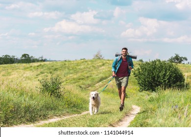 Traveler Running With Dog On Path On Summer Meadow