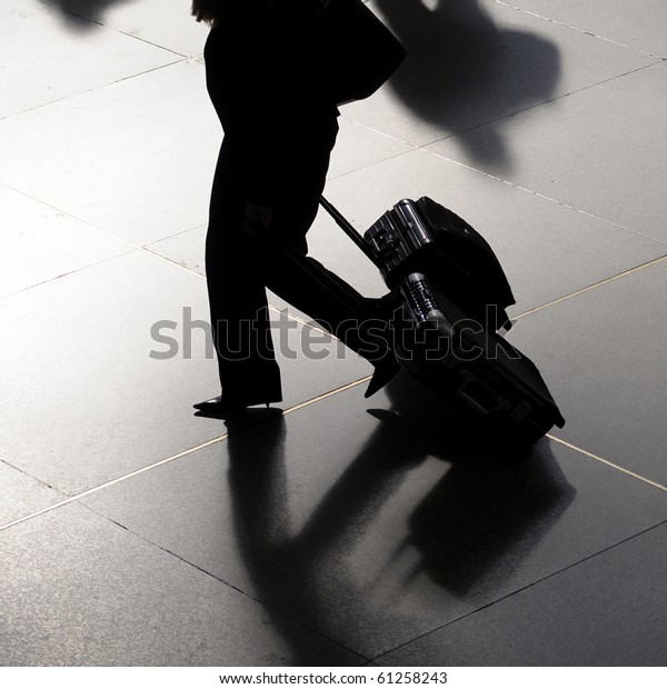 Traveler silhouette of business woman at\
airport walking with\
suitcases