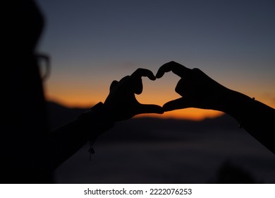 Traveler Silhouette Hands Heart Sign, Heart Shape Over Sunslight Sky Background. View Mountaion Light With Mist Morning On Lifestyle Holiday. Focus On Hands Shape