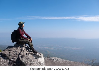 A traveler sits on a rock on a high mountain with a beautiful view of the sky. - Shutterstock ID 2170911713
