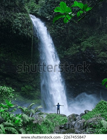 A traveler standing enjoying a waterfall in the forest, Ciparay Waterfall, Tasikmalaya, West Java, Indonesia
