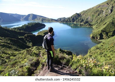 traveler stands on a cliff above the volcanic lake lagoa do fogo in sao miguel, azores, and enjoys amazing view.