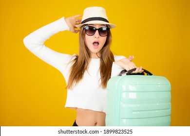 Traveler teenager holding a suitcase isolated on yellow background in vacation with suitcase and passport